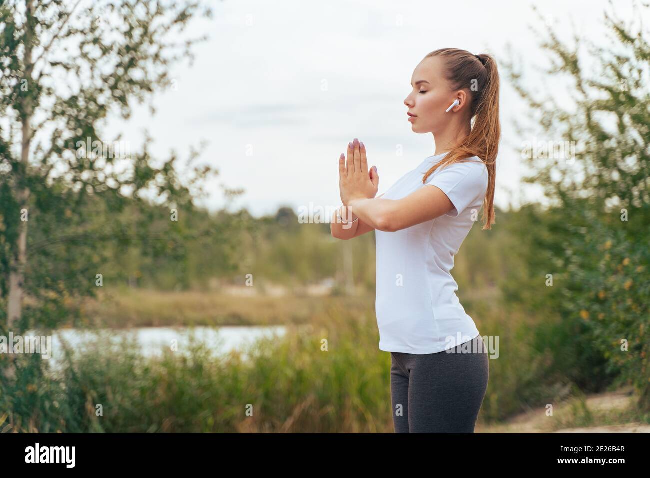 Slender girl is engaged in yoga, on the lake Stock Photo