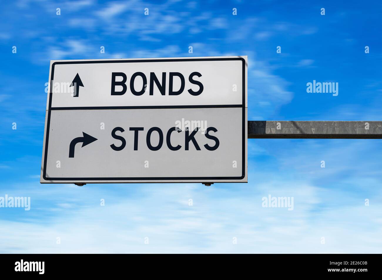 Road sign with words bonds and stocks. White two street signs with arrow on metal pole on blue sky background. Stock Photo