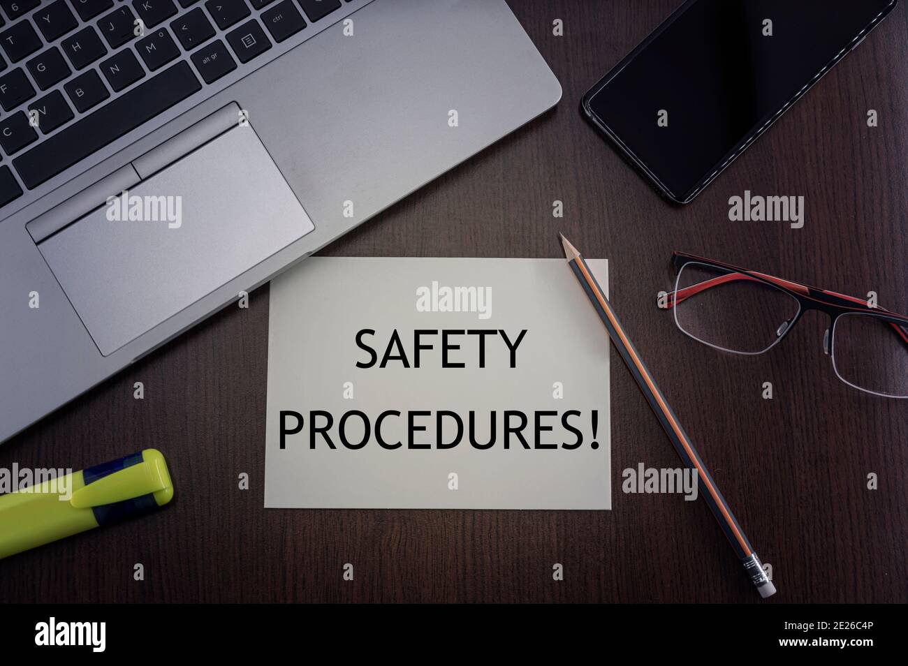 Top view of laptop, phone, glasses and pencil with card with inscription safety procedures. Stock Photo
