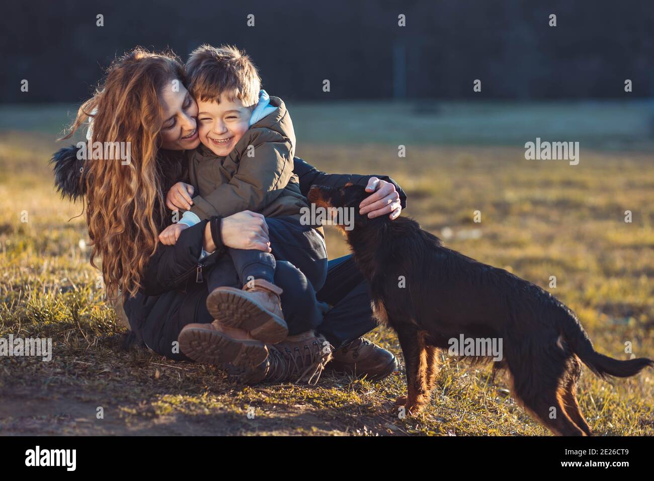 Young mom teaching protecting her son from a stray dog Stock Photo