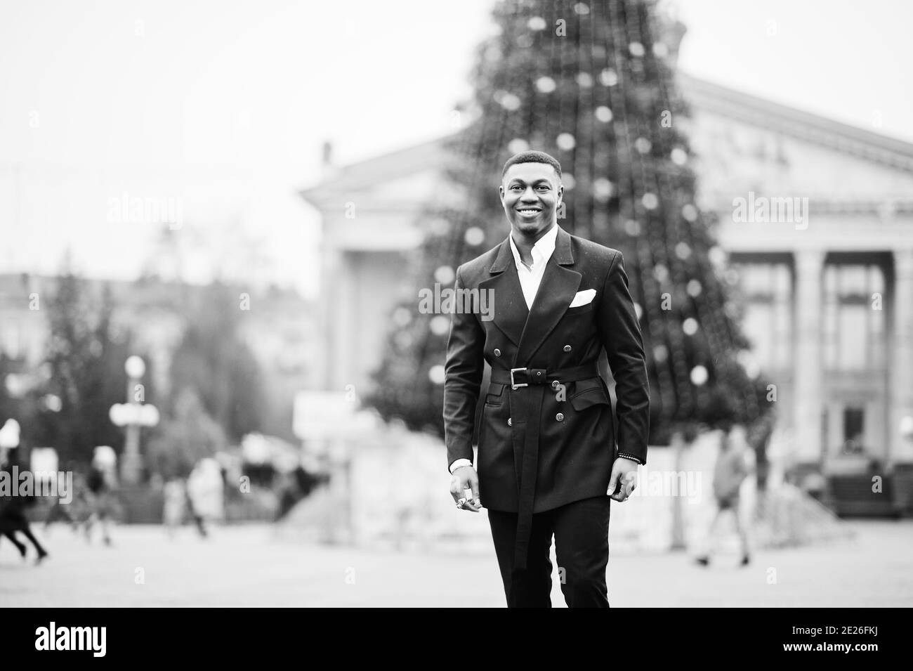 Portrait of young and handsome african american businessman in suit against main Christmas tree on the city square. Stock Photo