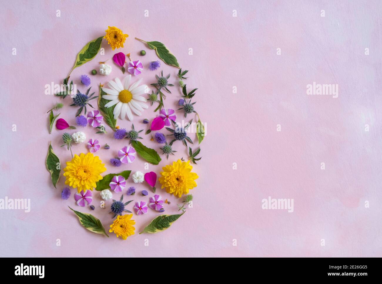 Easter egg shape made of colorful spring flowers and green leaves ...