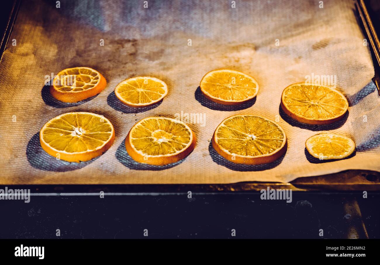 Drying fresh orange slices on oven pan. Making arts and crafts supplies. Dry slices cooking. Stock Photo