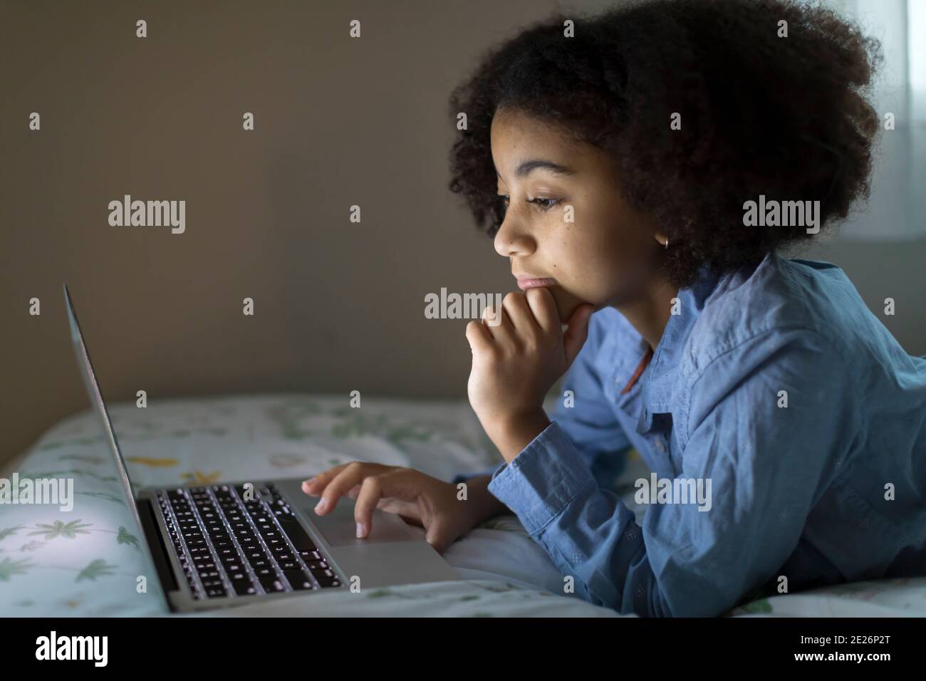 Side view of an ten year-old bi-racial girl working on her laptop Stock Photo