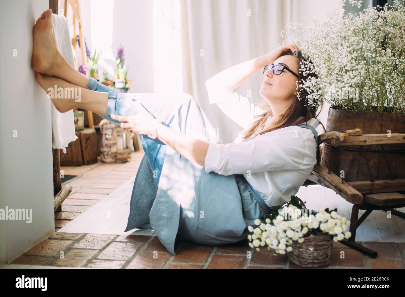 Beautiful young girl in an apron among the flower shop. Spring