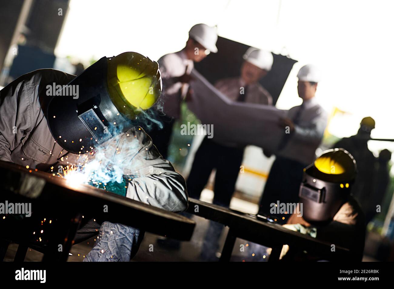 Welders at work on the factory floor with management planning Stock Photo