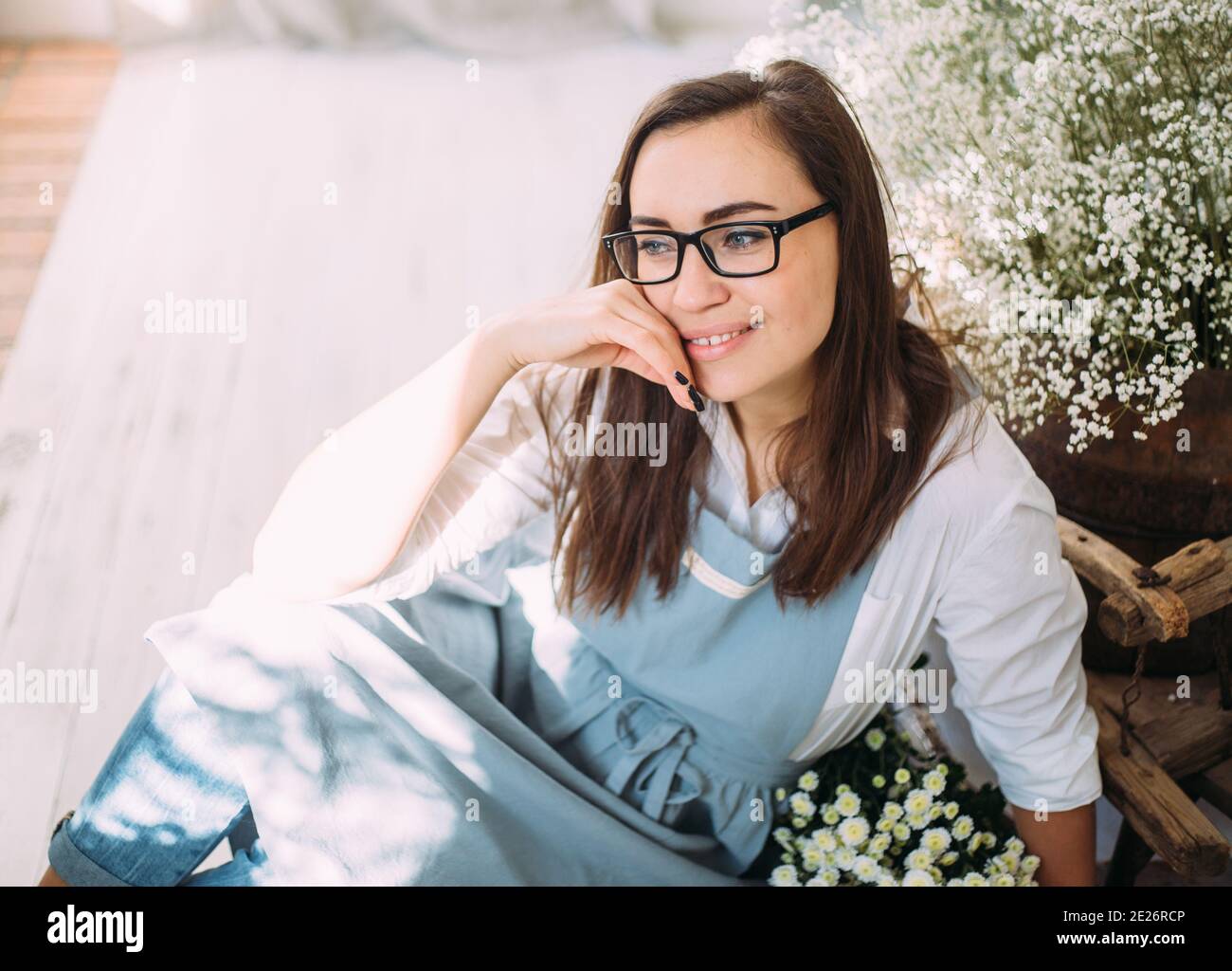 Beautiful young girl in an apron among the flower shop. Spring