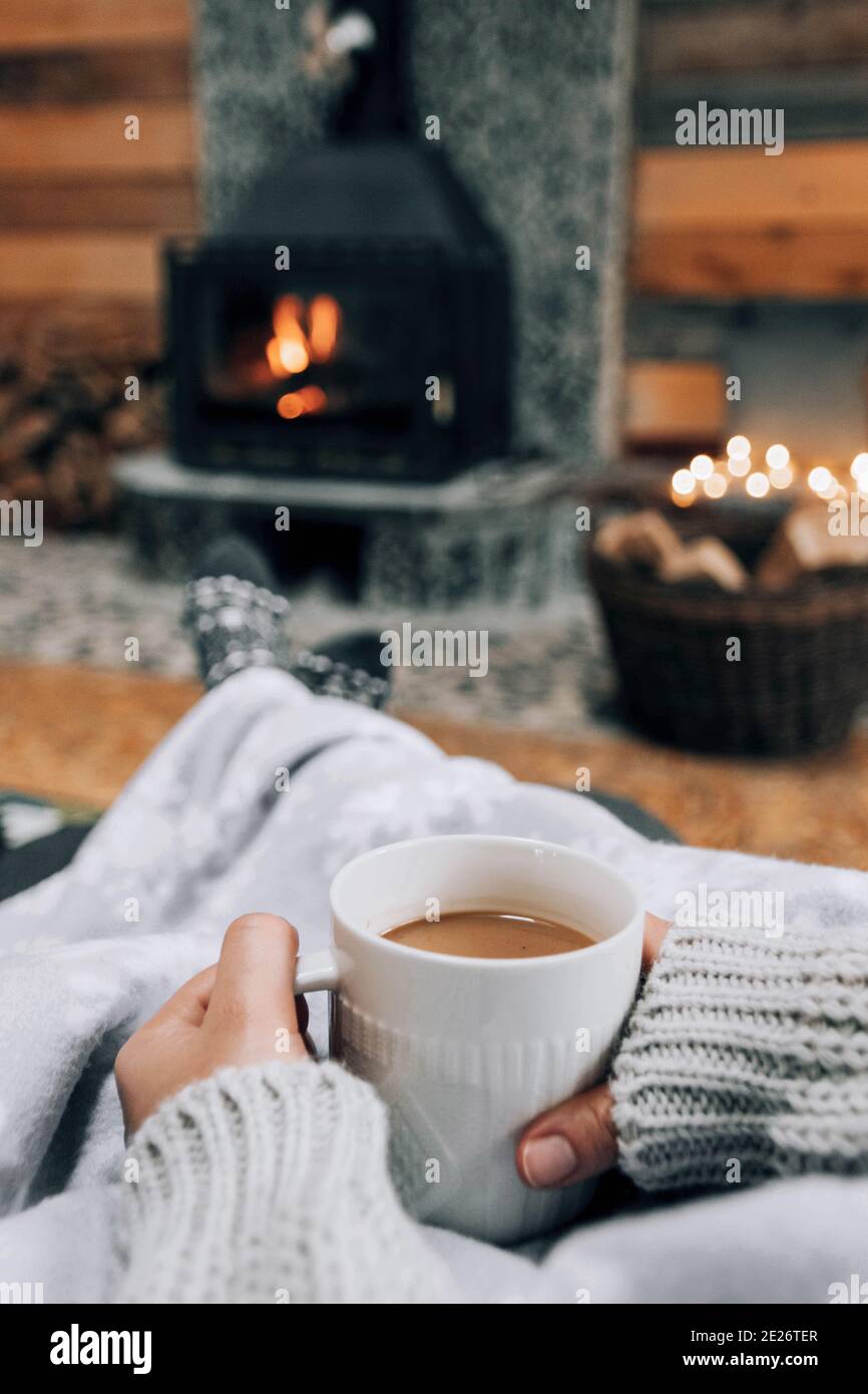 Shallow focus shot of hands holding a mug of coffee on fireplace background Stock Photo