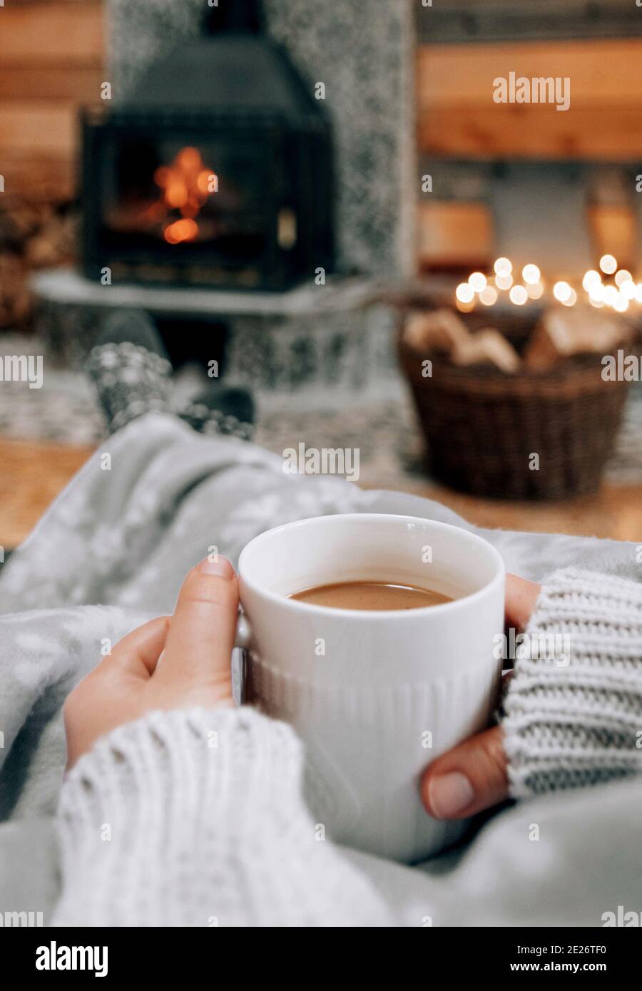 Shallow focus shot of hands holdings a mug of coffee on fireplace background Stock Photo