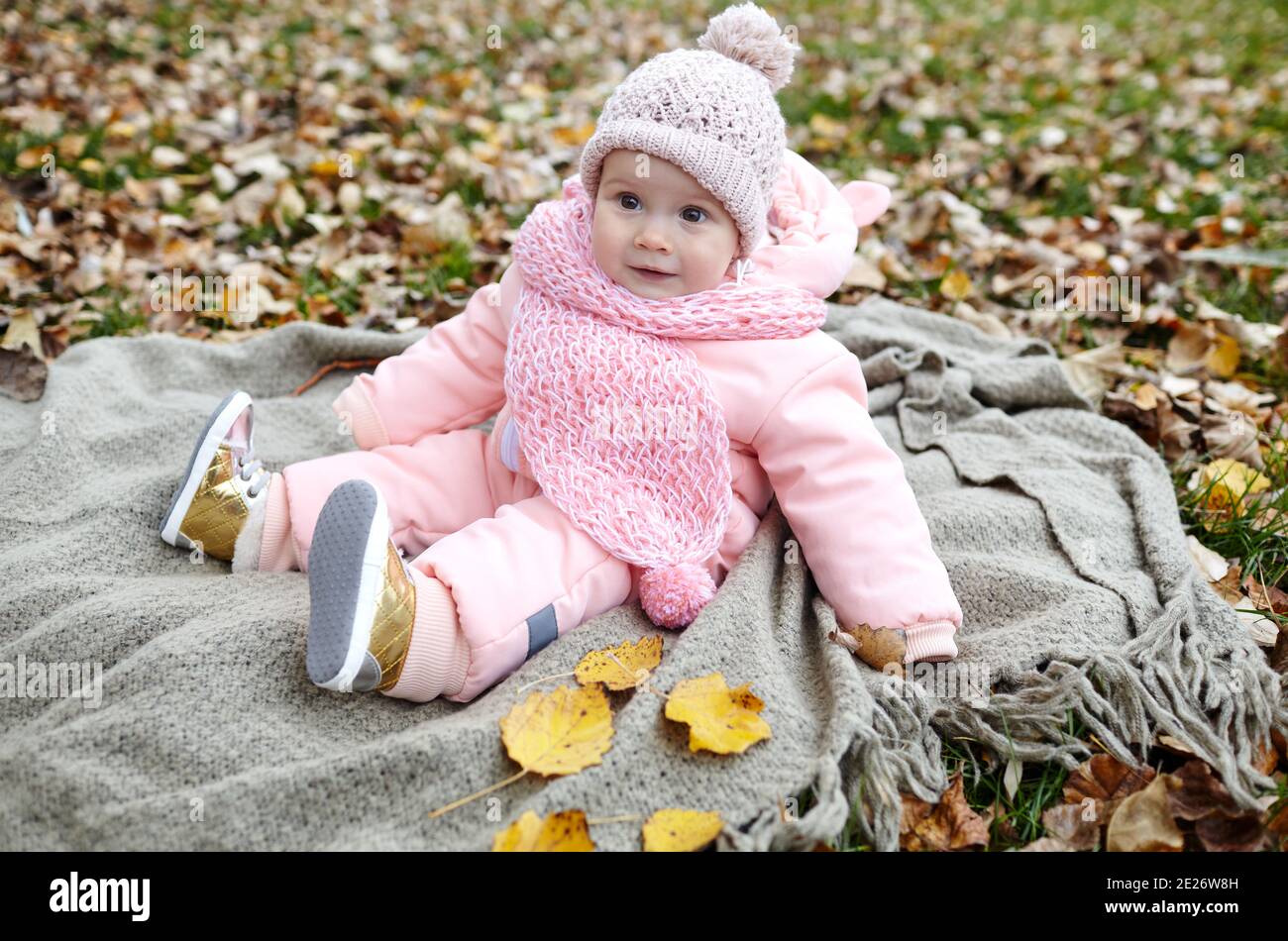 Beautiful baby girl sitting on the plaid. Child outdoor. Adorable