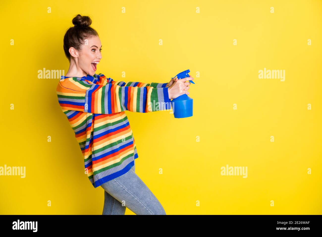 Photo of crazy positive young lady look point sprayer empty space wear jeans isolated on yellow color background Stock Photo