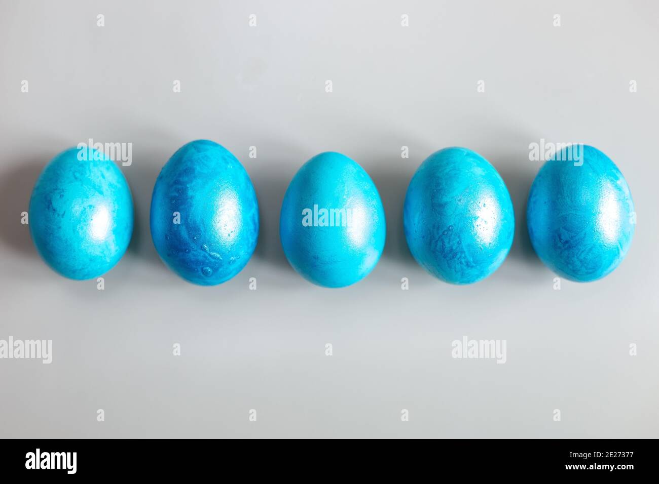 Row of five blue Easter eggs on grey background Stock Photo