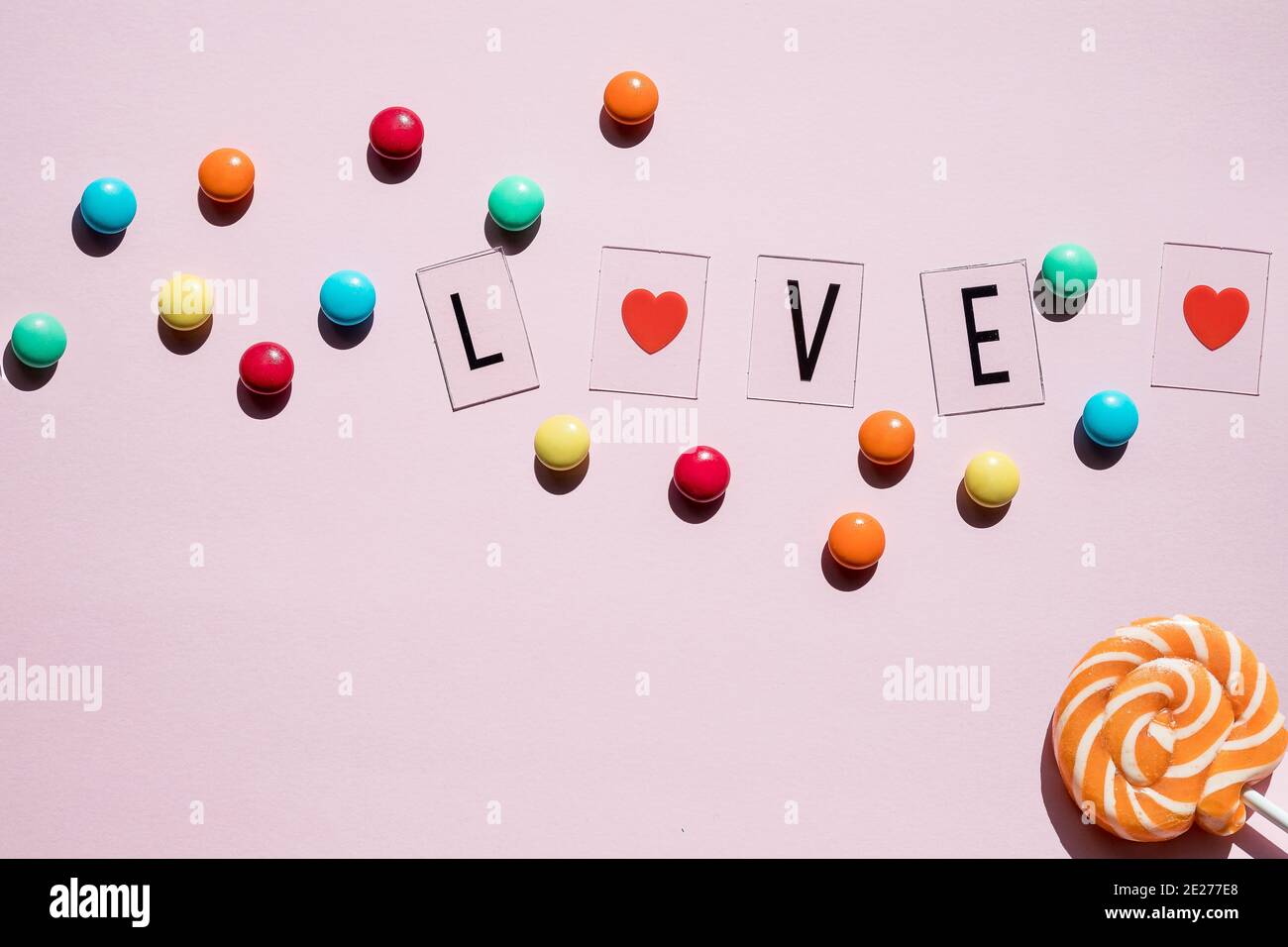 Pink candies, lollipops and jelly beans on white wooden background