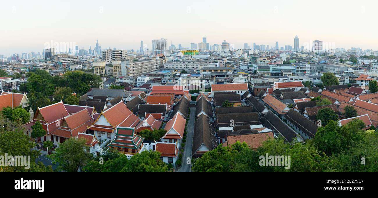 Aerial view of Bangkok city. Orange rooftops of Buddhist monastery buildings on a foreground. View from Golden Mount Wat Saket. Stock Photo