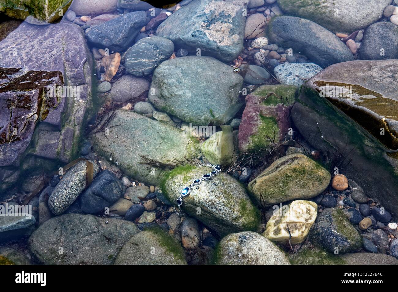 A storm washed away a jewellery to the sea coast rocks. Stock Photo