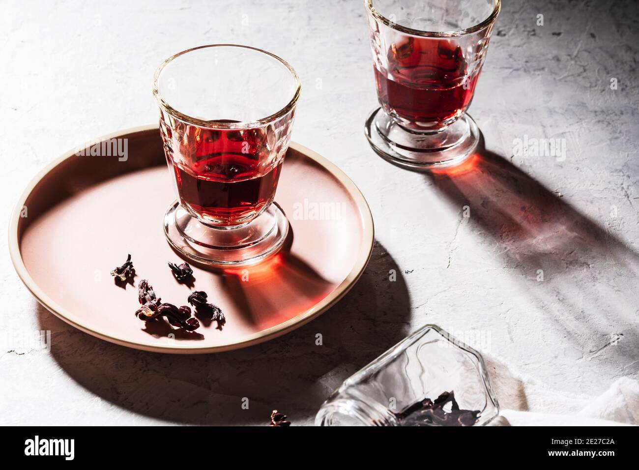 Refreshing fruit herbal tea in glasses, ripe pomegranate on plate, hibiscus tea and dry rose petals, hard light with harsh shadows Stock Photo