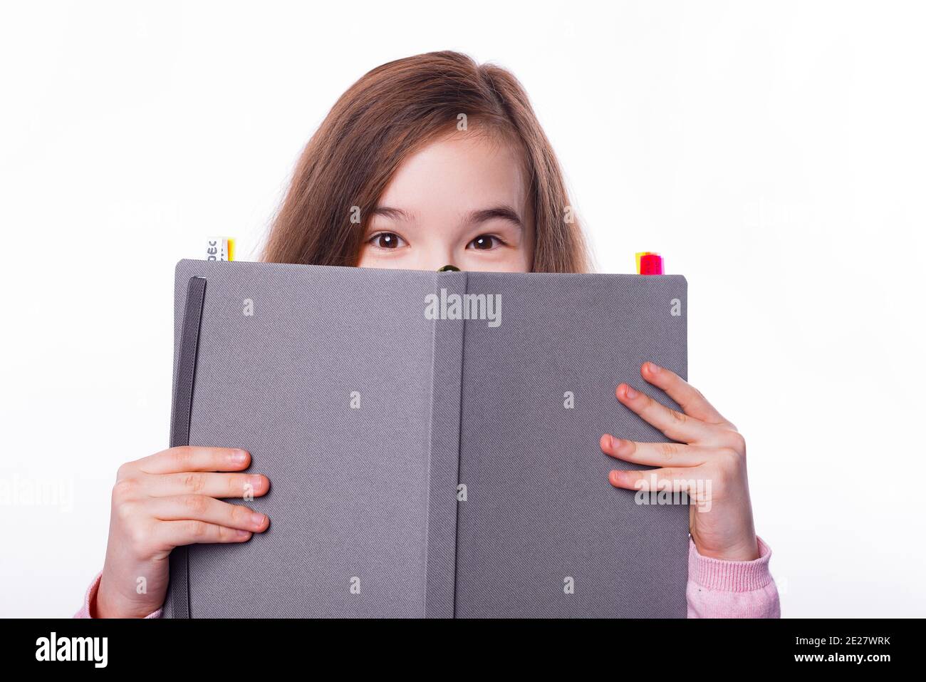 Close up photo of young school girl covering face with planner. Stock Photo