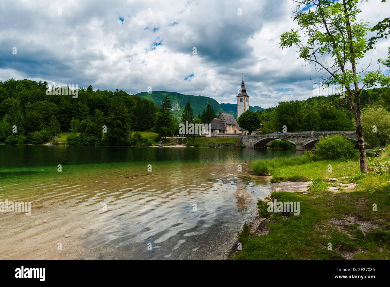 The church of St John the Baptist and the stone bridge on lake Bohinj ...