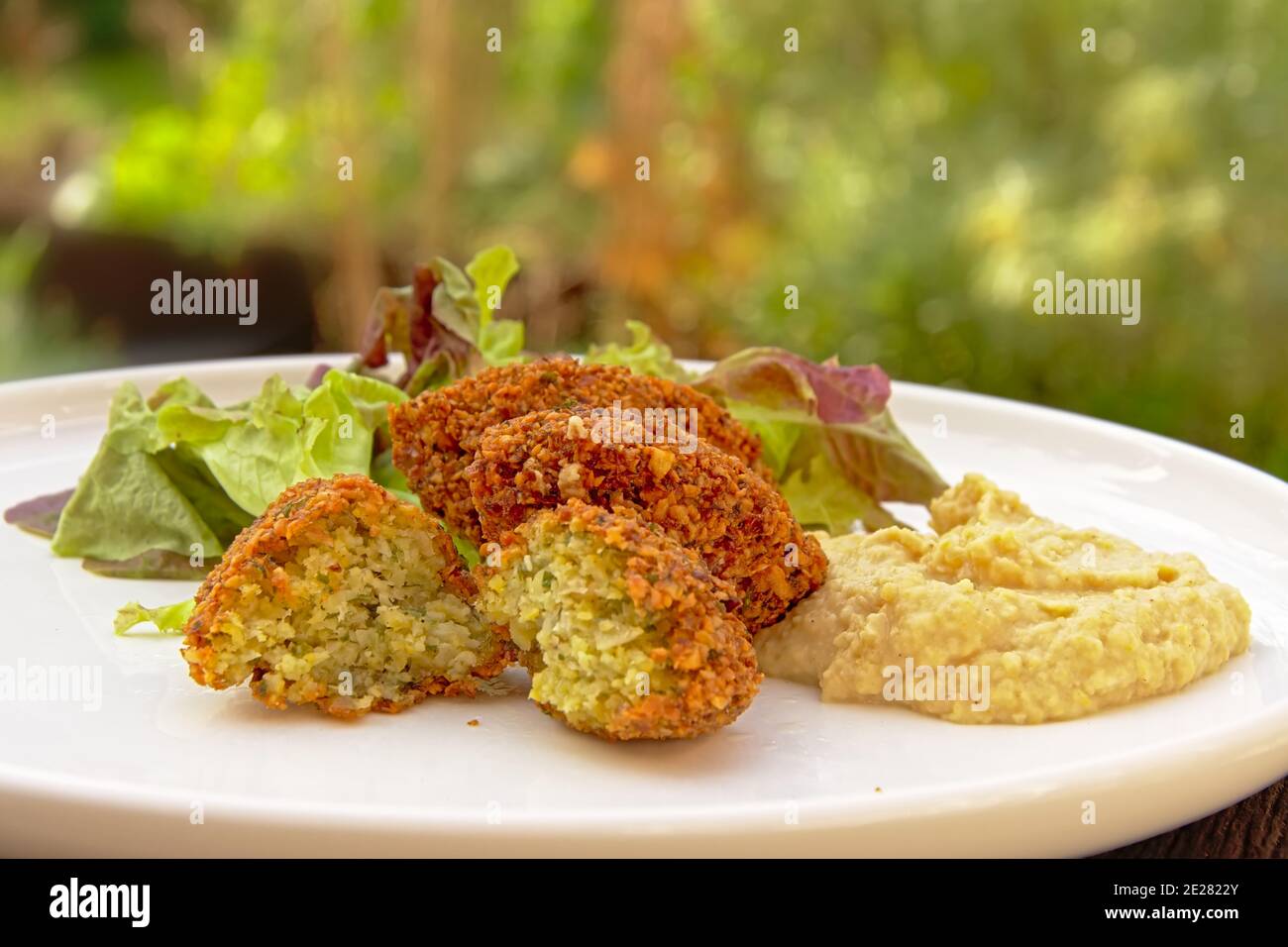 Download preview Three falafel balls, houmous and salad on a plate, middle eastern food. selective focus Stock Photo
