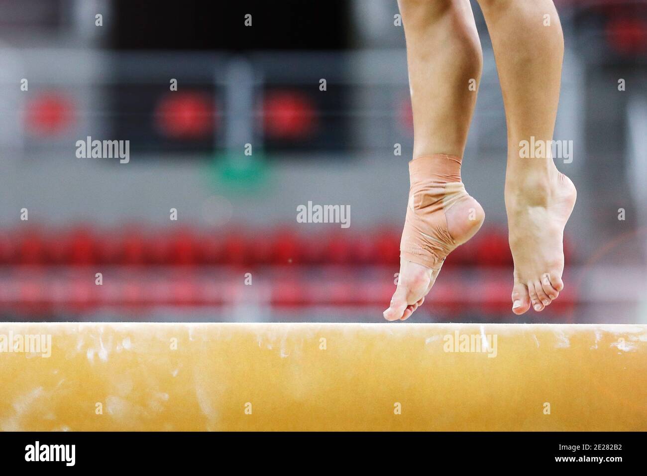 Balance beam artistic gymnastics competition performance. Close up detail of woman athlete feet on air, jump training session exercise indoors Stock Photo