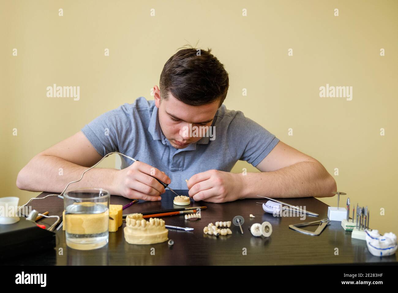 Dental technician modelling tooth crowns with hot wax. Workplace of a