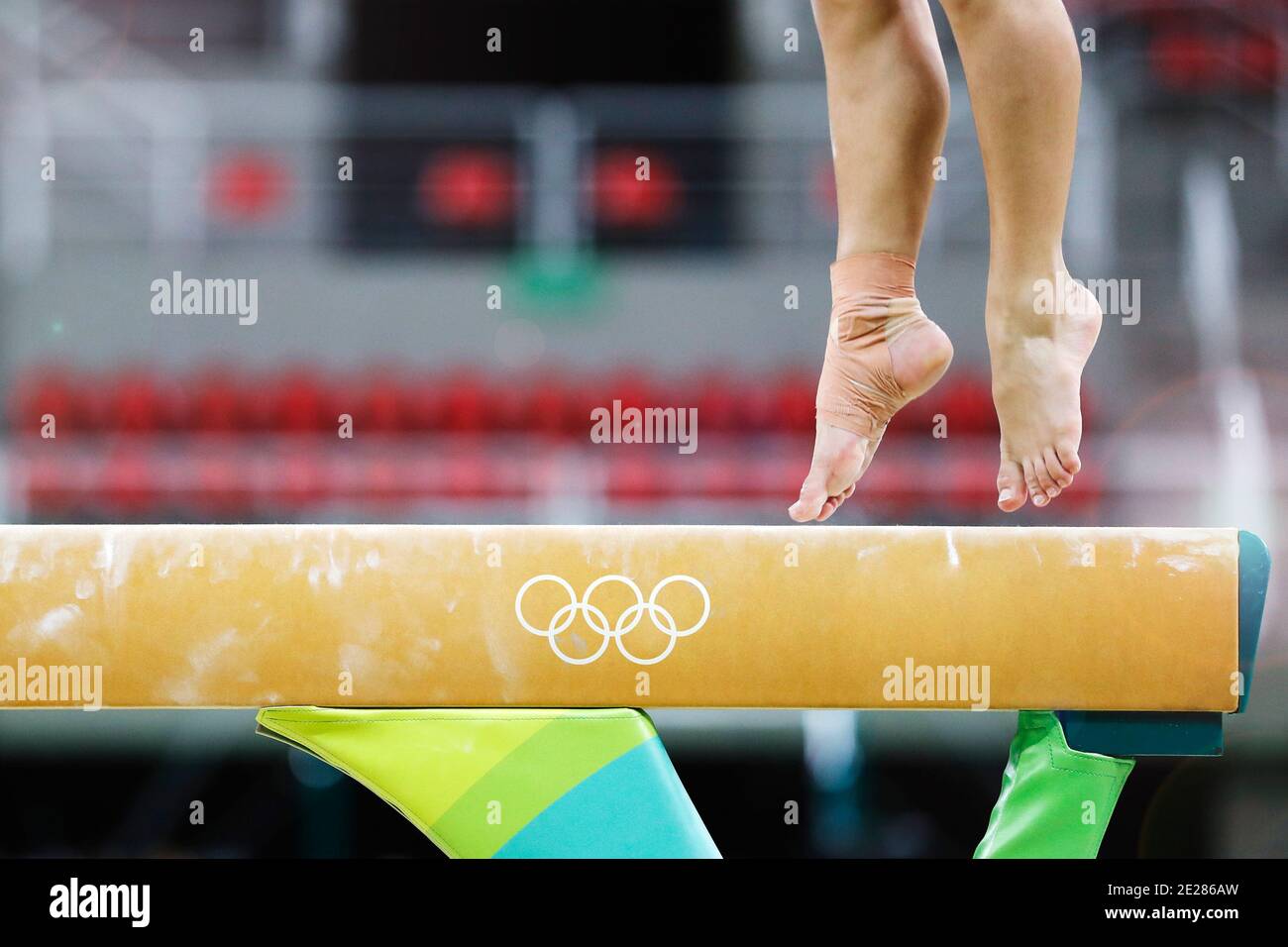Balance beam artistic gymnastics competition performance. Close up detail of woman athlete feet on air, jump training session exercise indoors Stock Photo