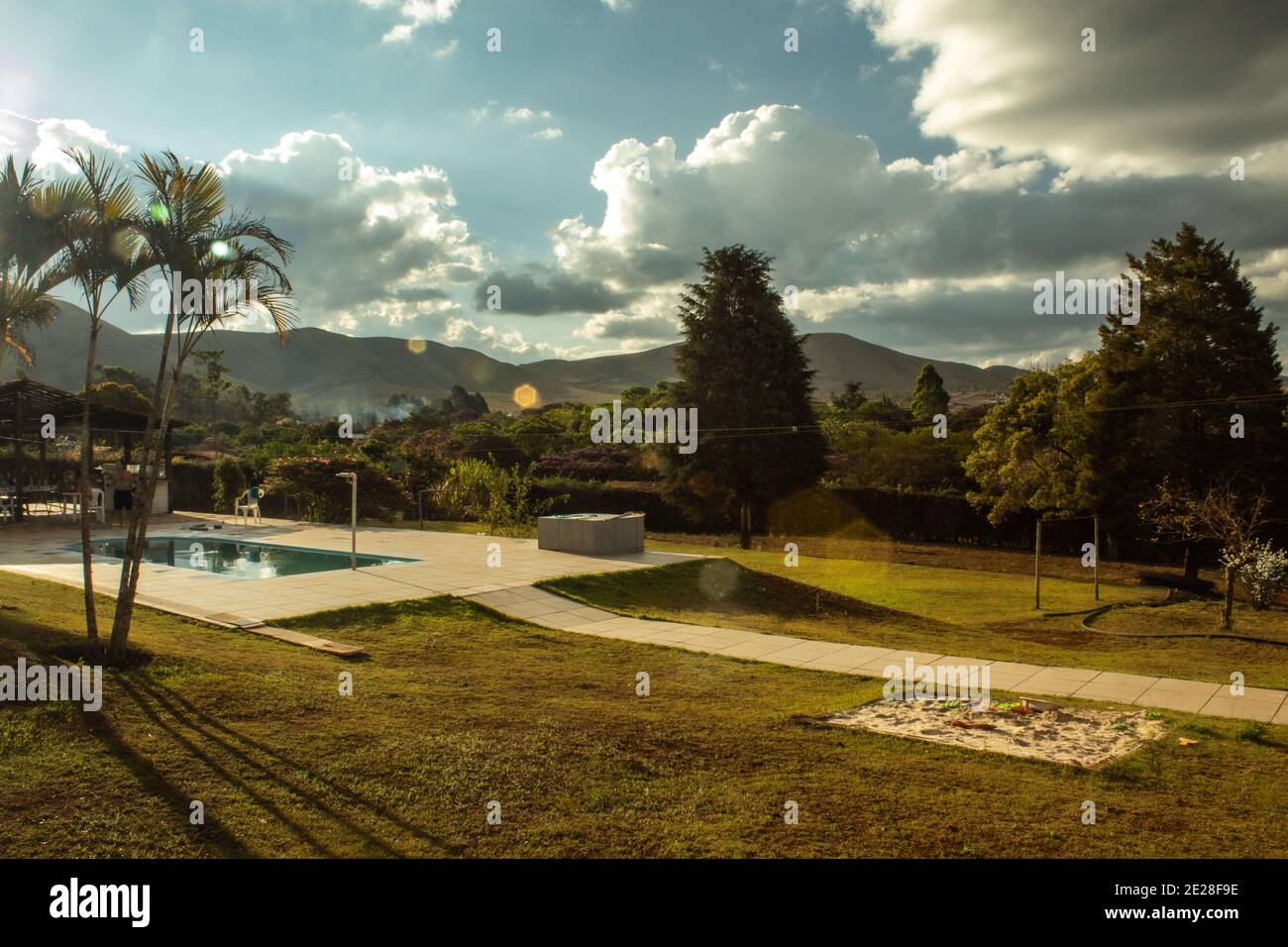 Photograph at sunset of country side landscape with mountains, trees and a pool, with lens flare. Stock Photo