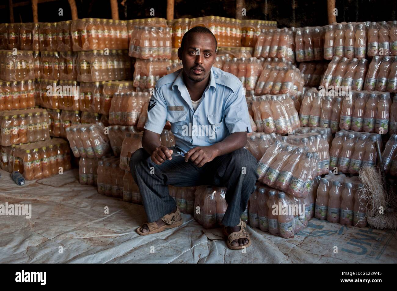 Abdi Mahat, 26 years old, from Kismayo, pictured at the Dadaab refugee camp in Kenya, on August 15, 2011. He came here in 1991. Abdi is a salesman. Paradoxically, nobody has been buying any drink since the beginning of the draught. Business is being worse everyday. Abdi belongs to the first generation of refugee who fled the 1991 Civil War in Somalia. He remembers how empty the area was, back in the days.There was nobody there. The forest was close, people were scared of wild animals such as hyenas. They were afraid of robbers as well. To him, they used to live more precariously than this new Stock Photo