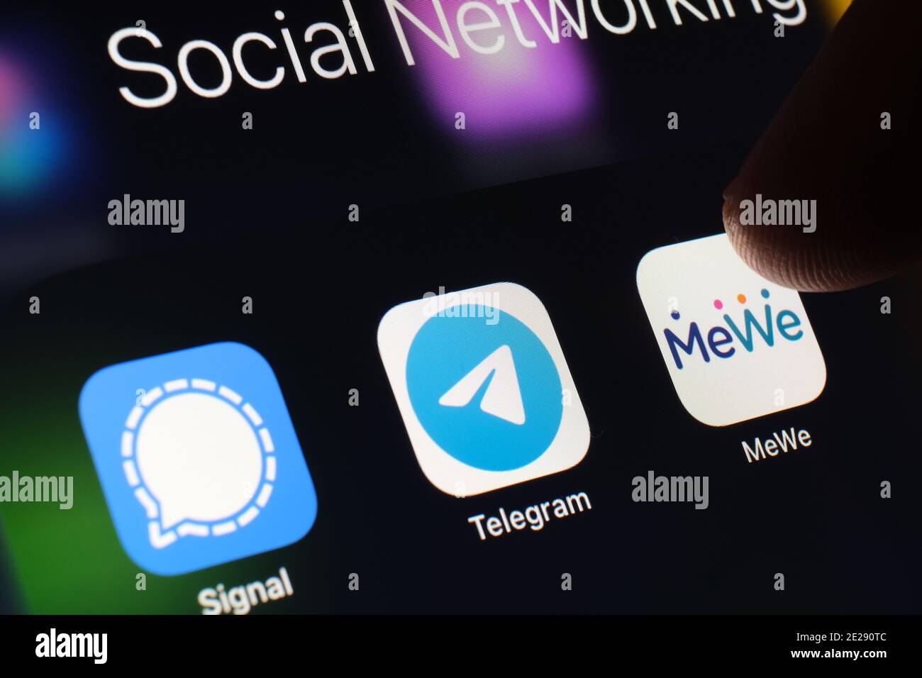 Stafford, UK - January 12 2021: Signal, Telegram, MeWe apps and blurred finger above them. Social network apps gaining popularity in the United States Stock Photo
