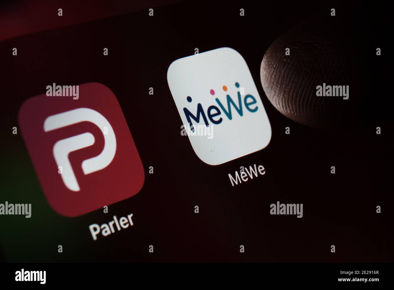 Stafford, UK - January 12 2021: Parler and MeWe apps and blurred finger above them. New social network apps popular in the United States. Concept. Stock Photo