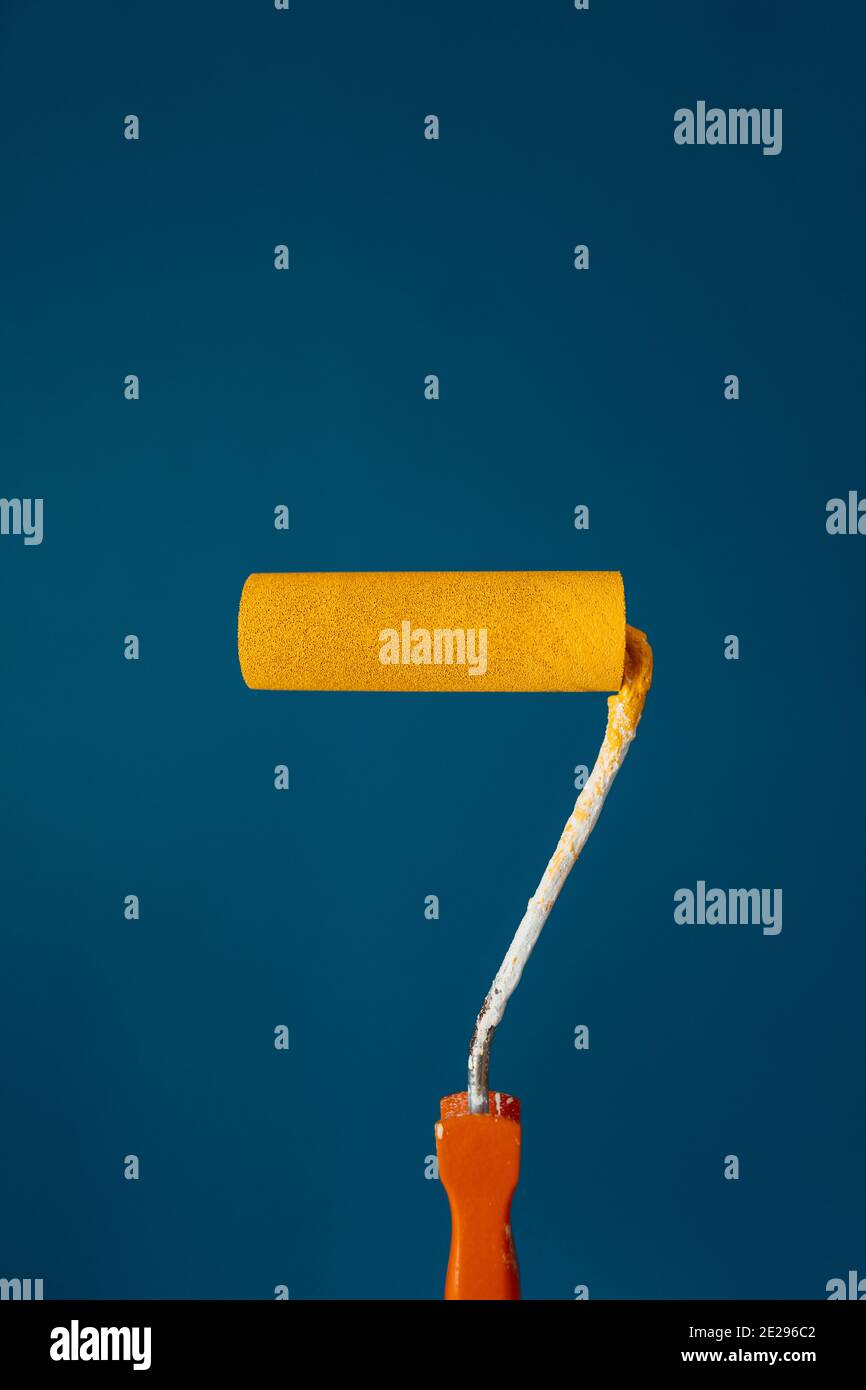 Painting roll with yellow paint over petrol blue background Stock Photo Alamy