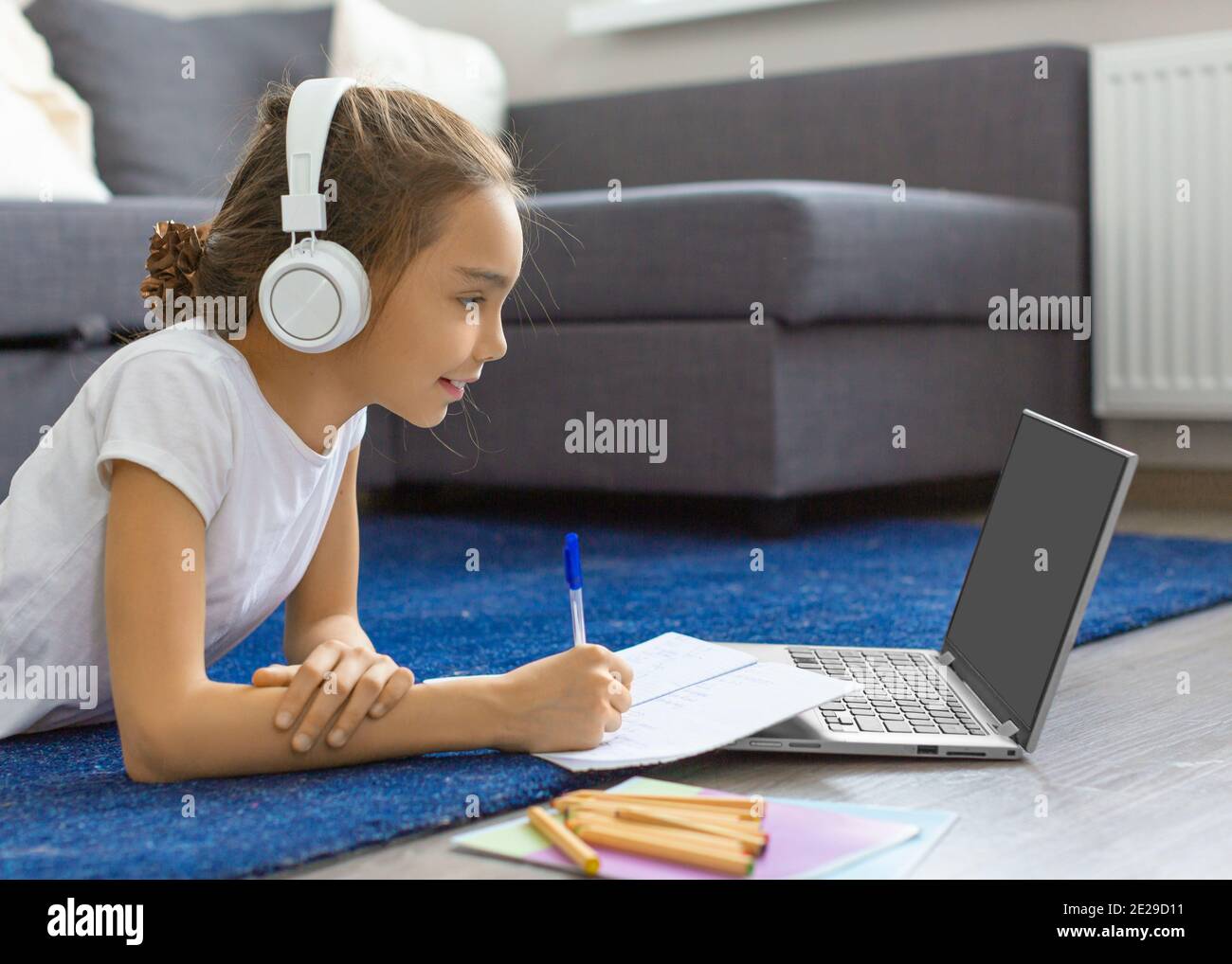 Teenager girl doing her homework online in front of a laptop monitor ...