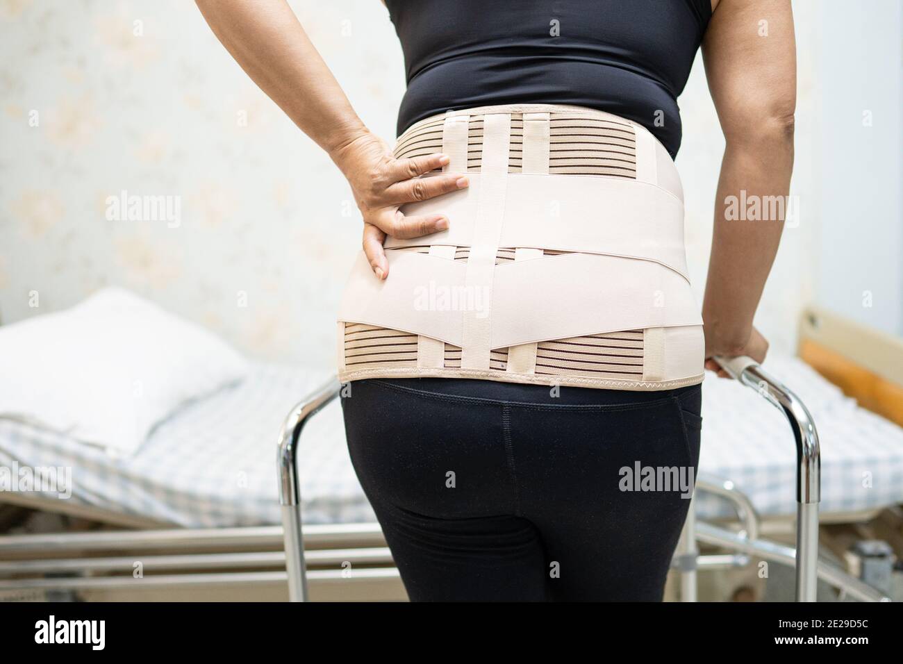 Asian lady patient wearing back pain support belt for orthopedic