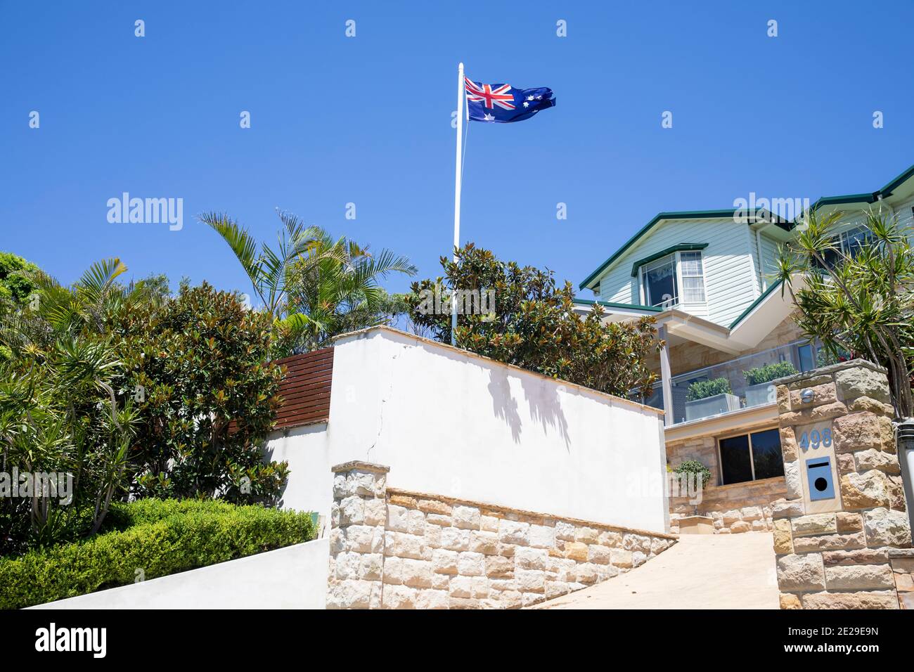 Sydney coastal detached home in Avalon Beach with lush garden and australian flag flying on flagpole,Sydney,Australia Stock Photo