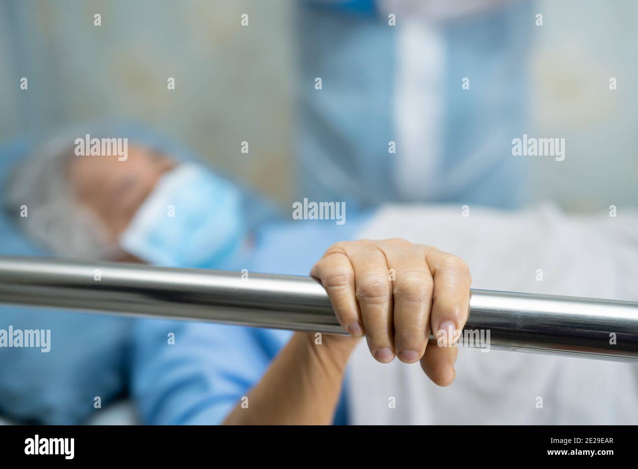 Asian senior or elderly old woman patient lie down handle the rail bed with hope on a bed in the hospital. Stock Photo