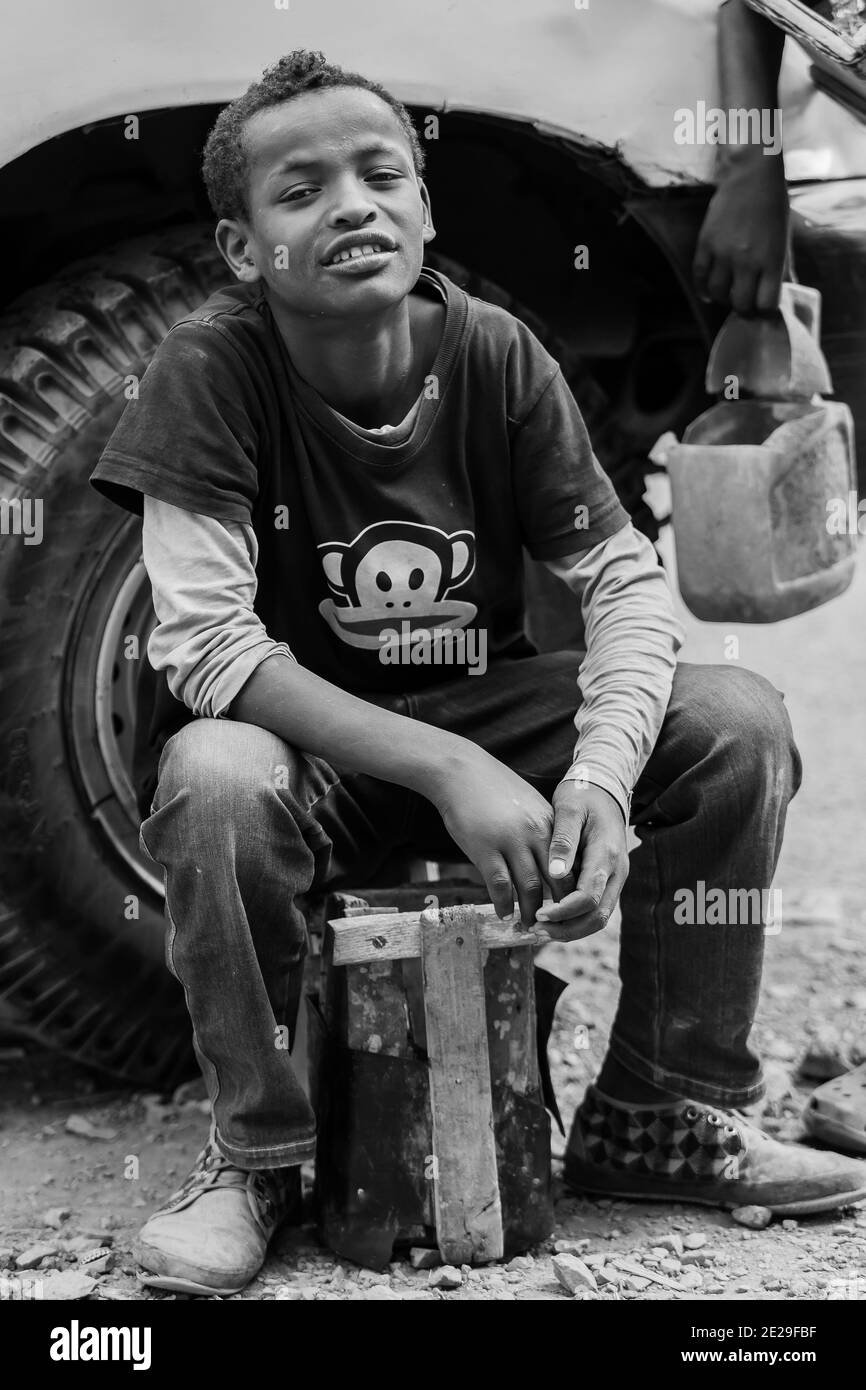 ADDIS ABABA, ETHIOPIA - Jan 05, 2021: Addis Ababa, Ethiopia, January 27, 2014, Young teenager working as a shoe shine boy on the street, looking strai Stock Photo