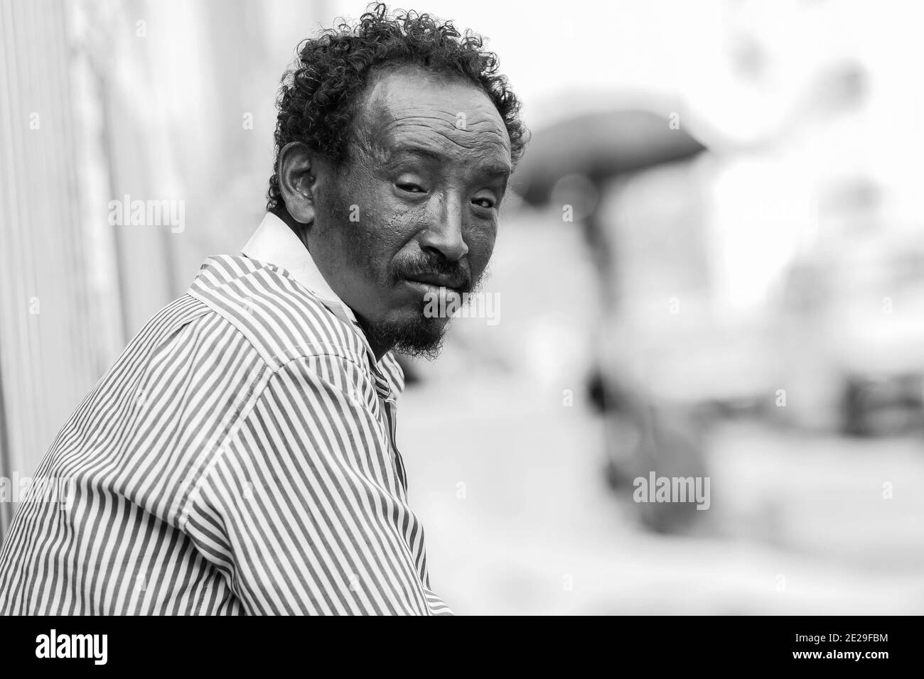 ADDIS ABABA, ETHIOPIA - Jan 05, 2021: Addis Ababa, Ethiopia, January 27, 2014, African man sitting on the street corner looking straight at camera Stock Photo