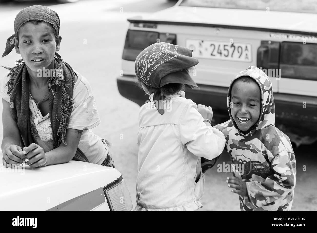 ADDIS ABABA, ETHIOPIA - Jan 05, 2021: Addis Ababa, Ethiopia, January 27, 2014, Three small orphan street kids playing and laughing on a quite city roa Stock Photo