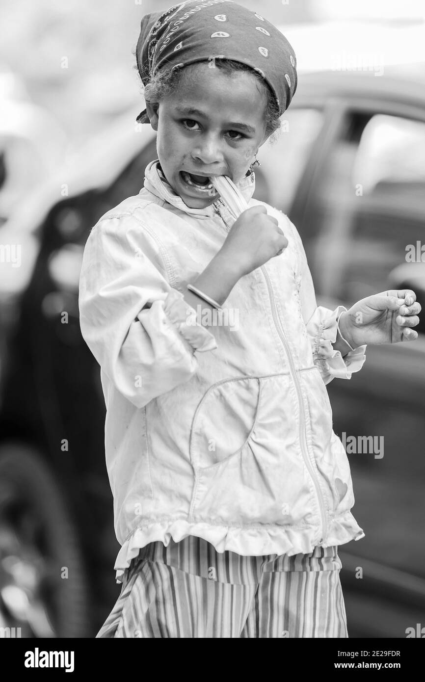 ADDIS ABABA, ETHIOPIA - Jan 05, 2021: Addis Ababa, Ethiopia, January 27, 2014, Young girl eating a piece of sugarcane on a quiet city street Stock Photo