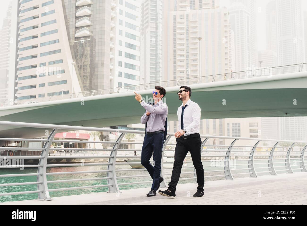 Business people on move. Two young successful architects in Dubai Marine walking and looking at their new business locations. Stock Photo