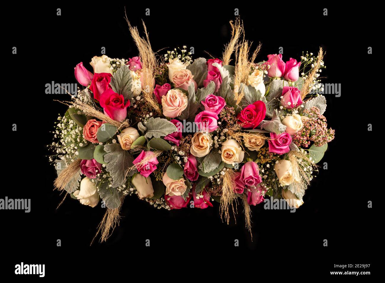 arrangement flower table centerpiece with pink tones roses and foliage. Isolated on black background Stock Photo