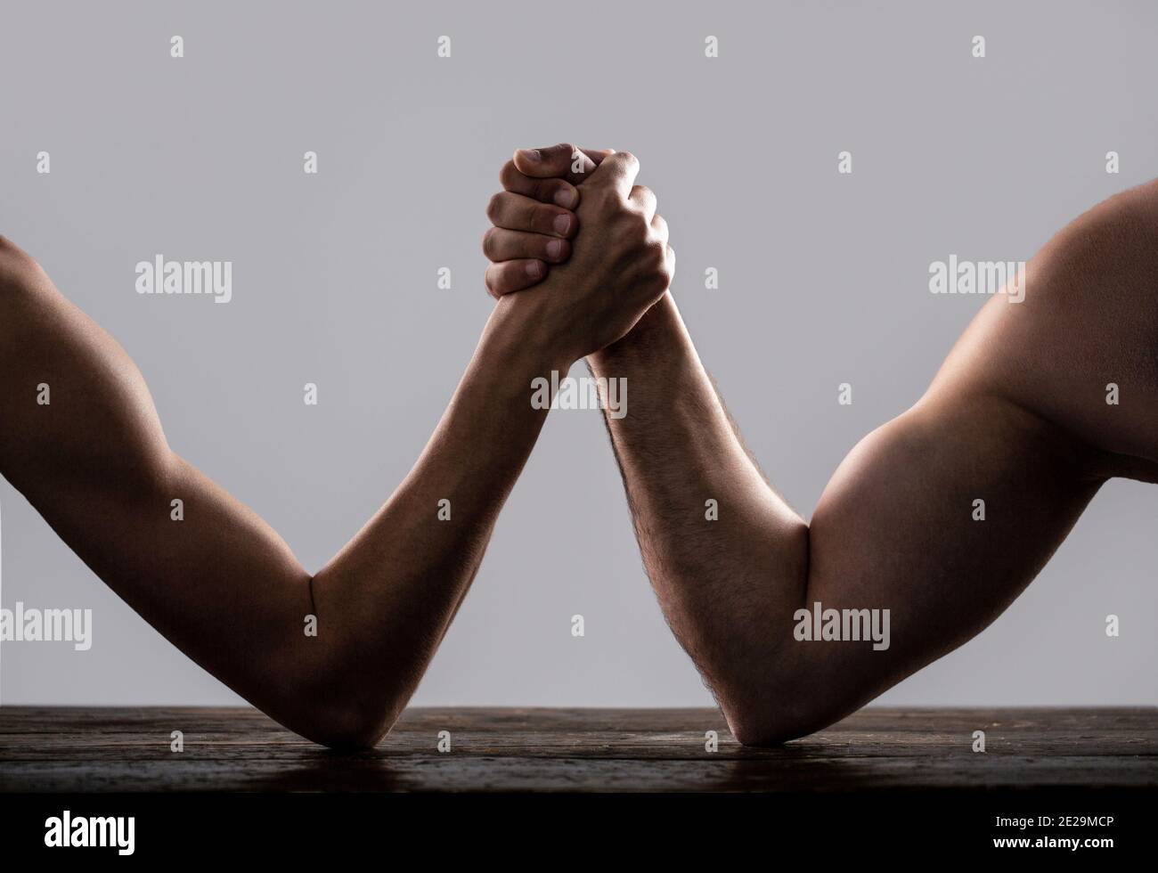 Arm wrestling. Heavily muscled man arm wrestling a puny weak man. Arms