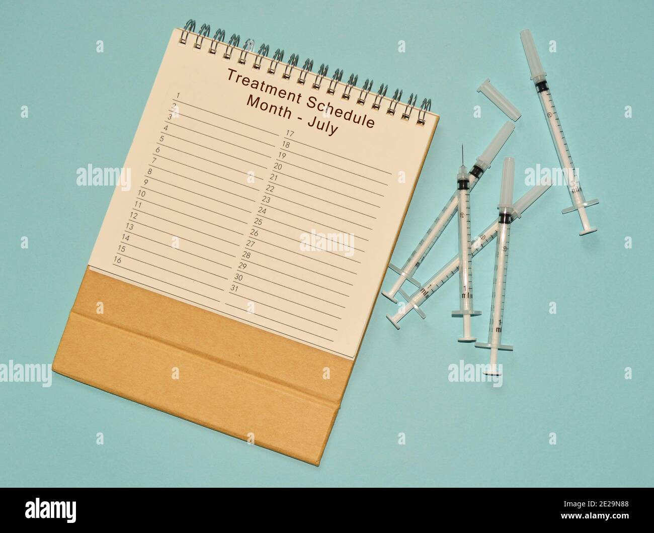 July treatment schedule calendar and disposable injection syringe on ...