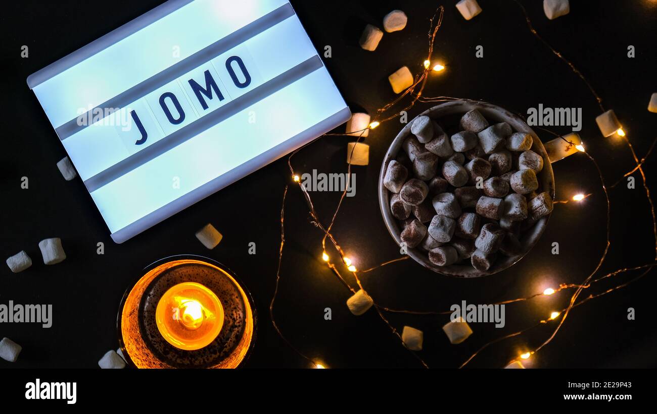 Lightbox with text JOMO Joy of Missing Out. The concept of relaxation from information and gadgets. Top view. Flat lay. Cup with cacao and Stock Photo