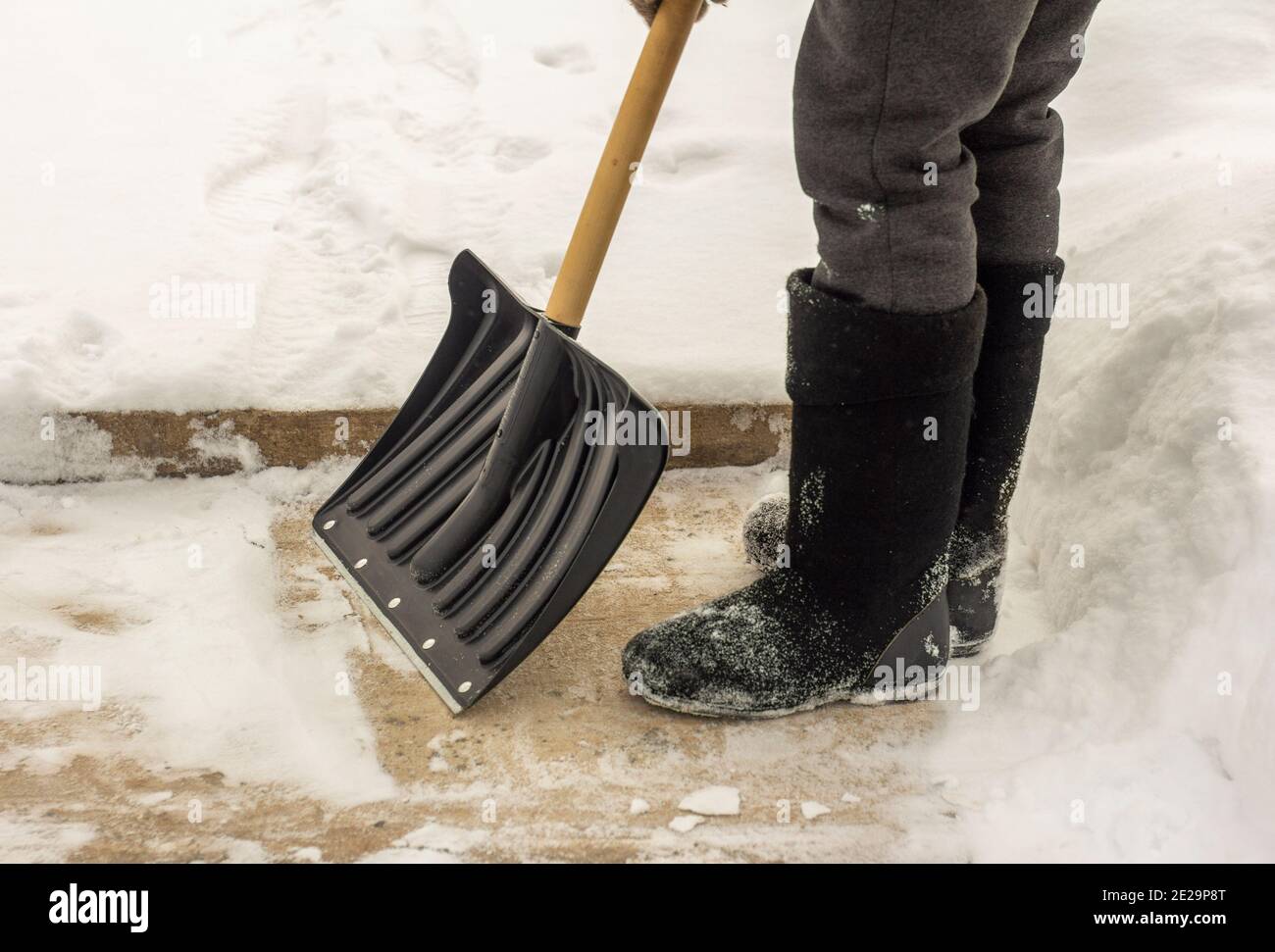 A man in felt boots, with a shovel in his hands, removes snow from the ...