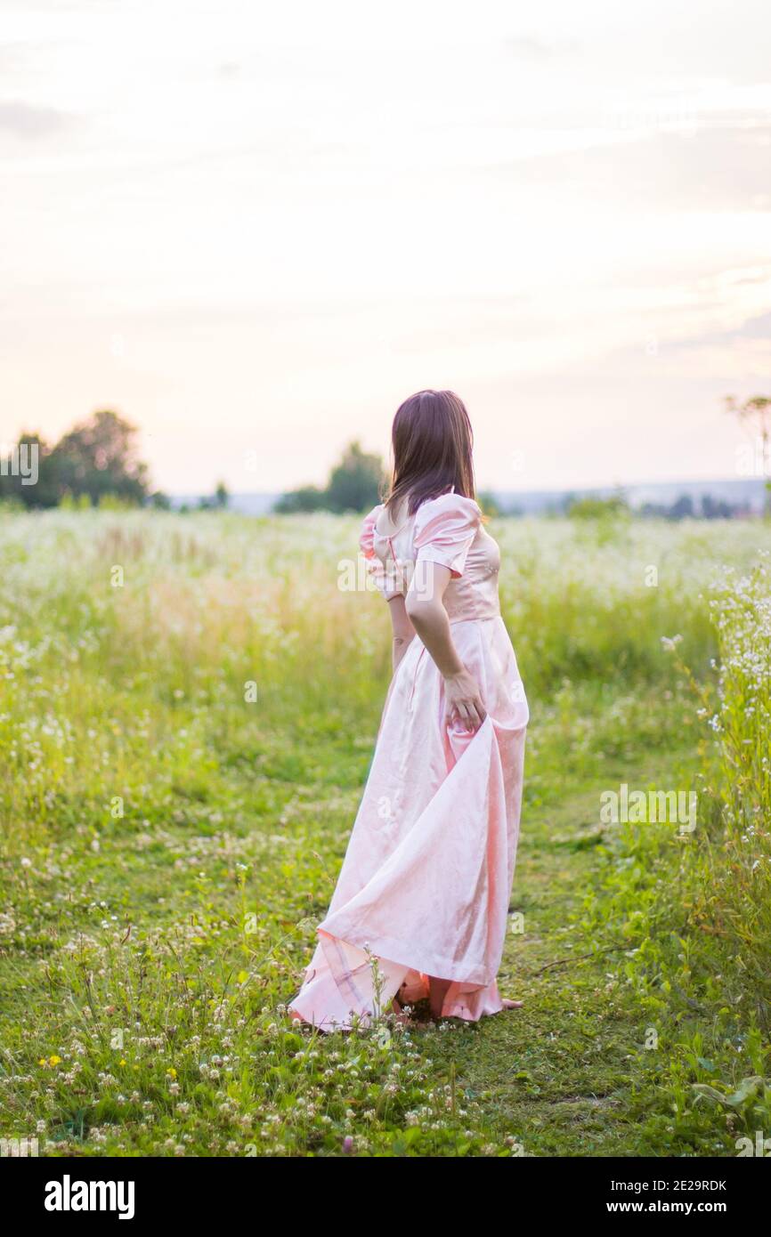 girl standing in the field in a pink dress Stock Photo - Alamy