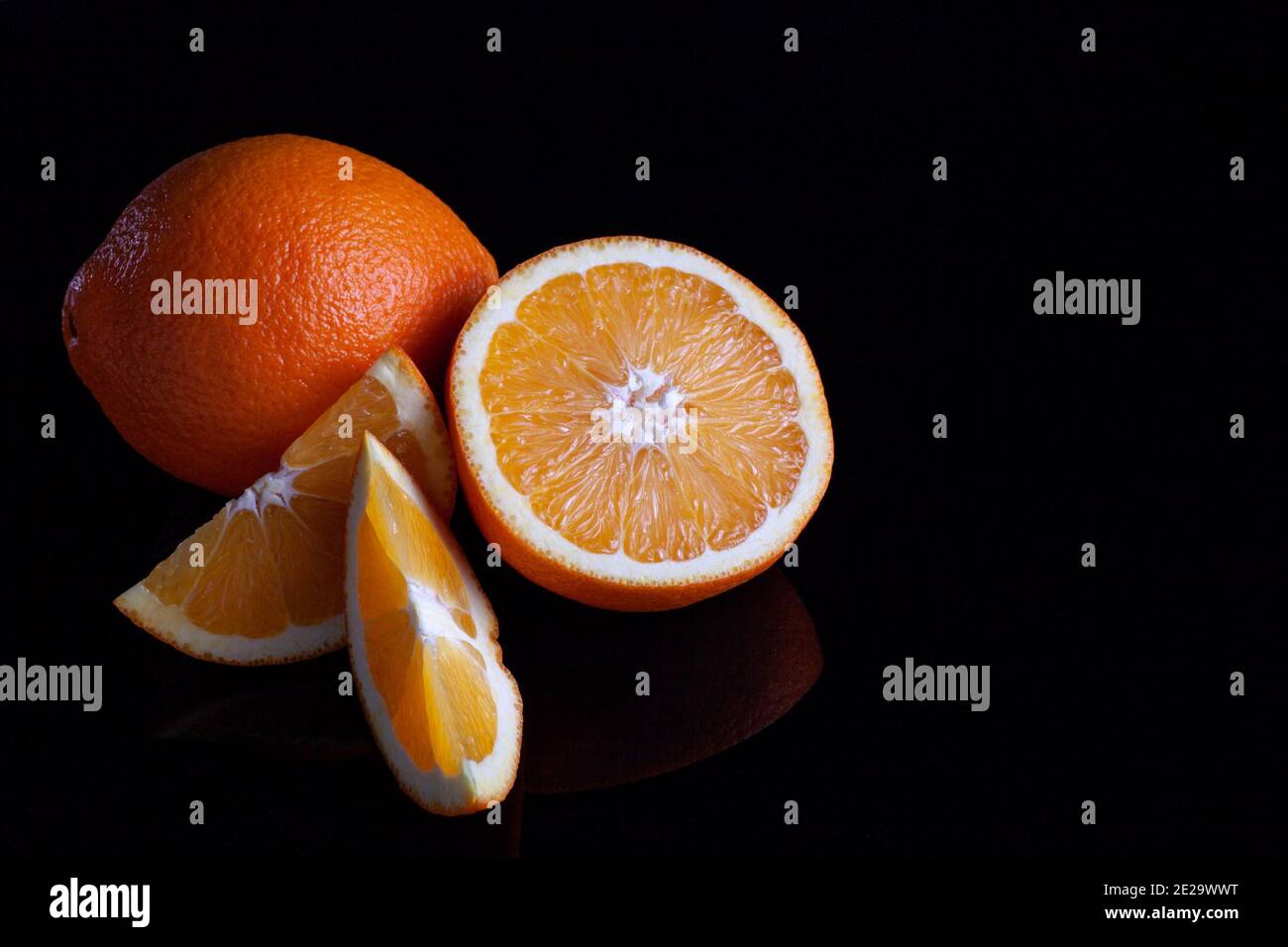 Ripe orange fruit sliced coposition on a black reflective background Stock Photo