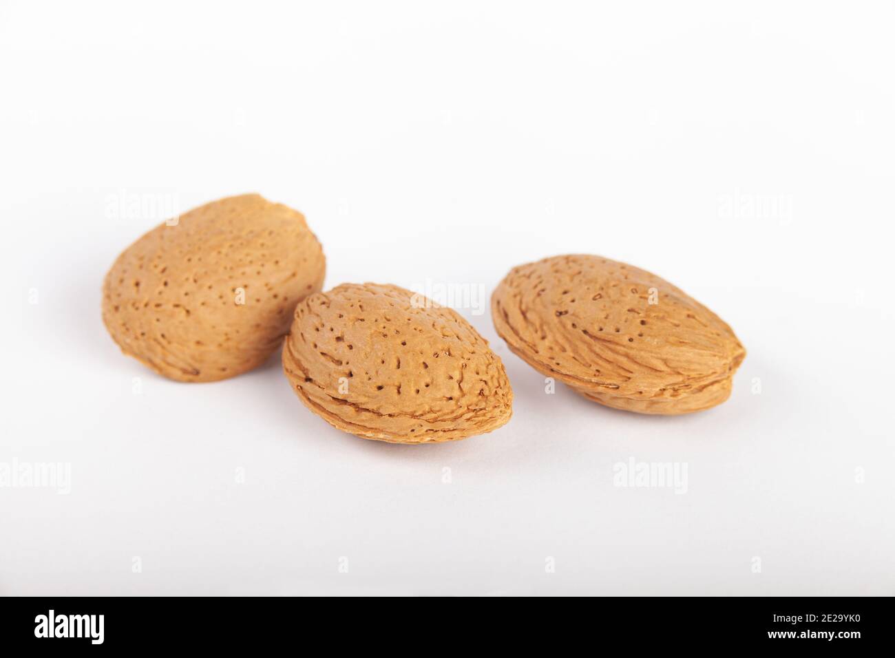 Three almond nuts in their shells Stock Photo