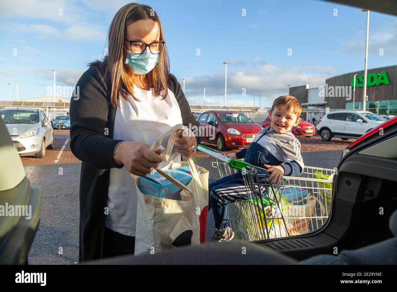 A mother wearing a face mask out shopping with her young child in Fife