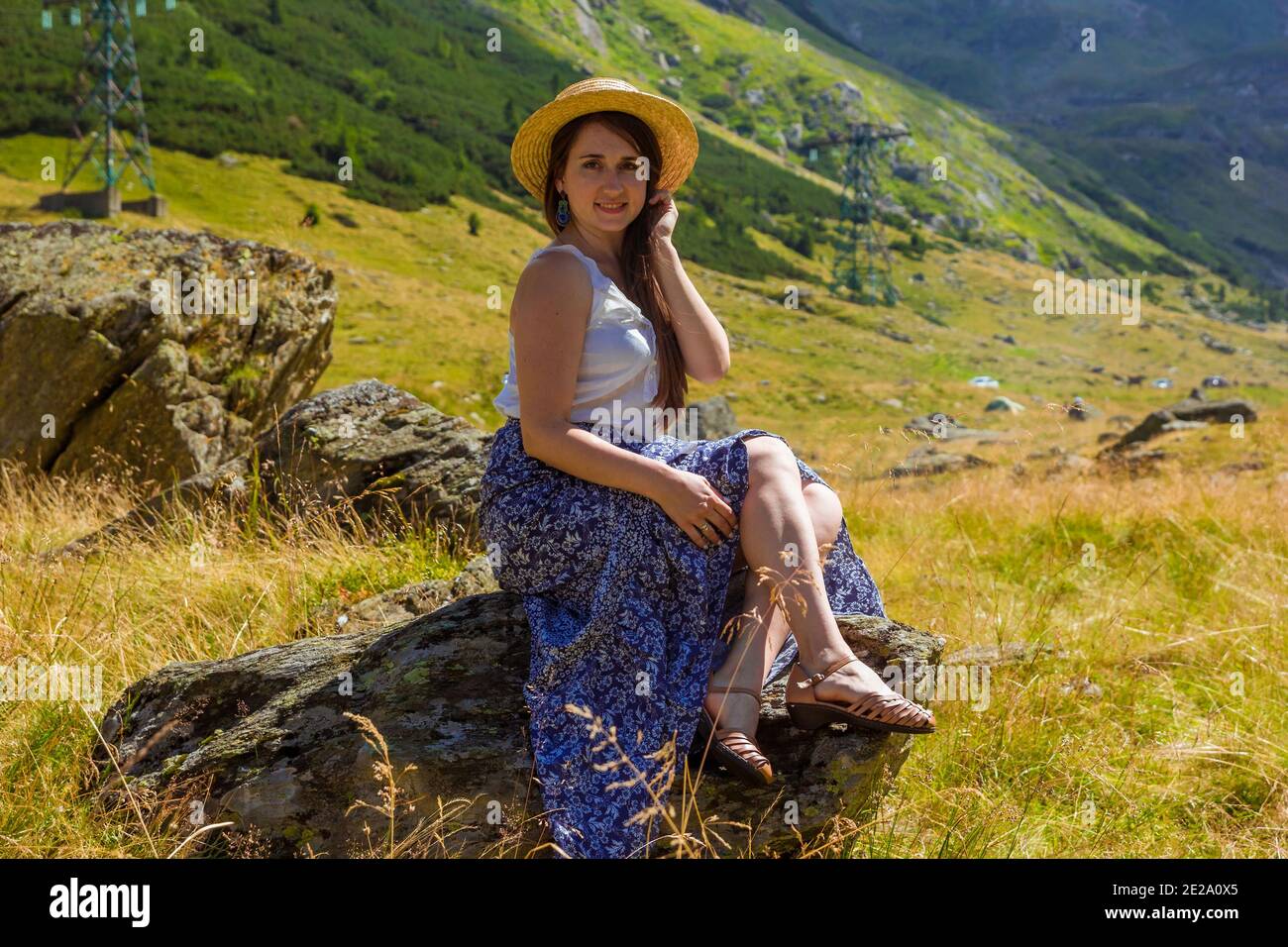 girl in dress sits on a rock holding a straw hat Stock Photo - Alamy
